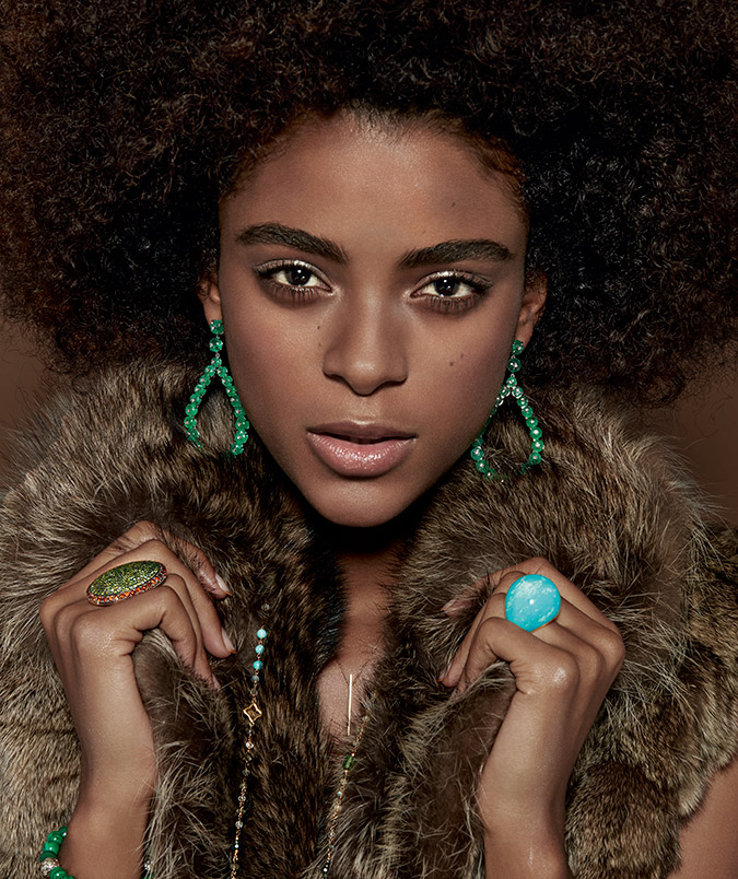 model in emerald earrings and turquoise ring with brown fur
