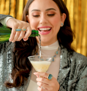 Parle model wearing opals and pouring champagne