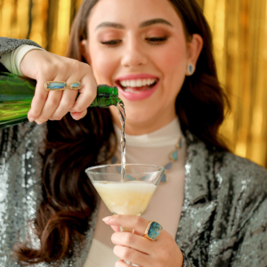 Parle model wearing opals and pouring champagne